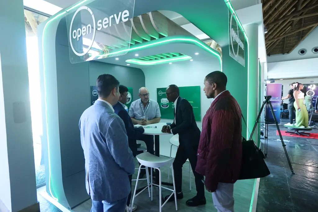 Business professionals having a discussion at the Openserve exhibition booth during a trade show or conference.