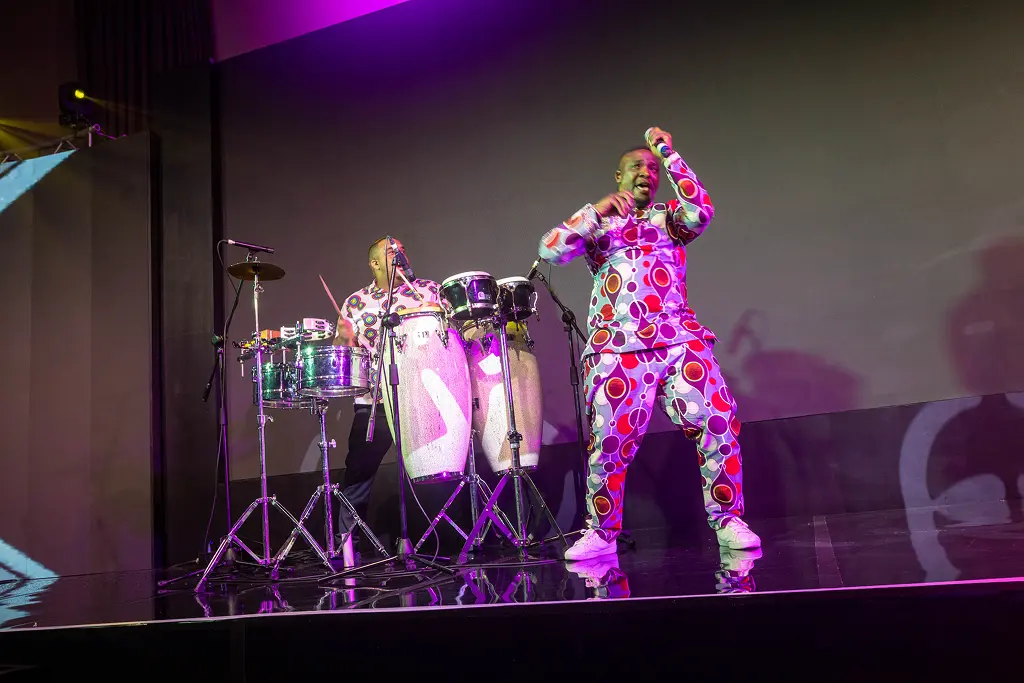 Performers in vibrant patterned outfits delivering a high-energy musical set on stage at SATNAC 2025.